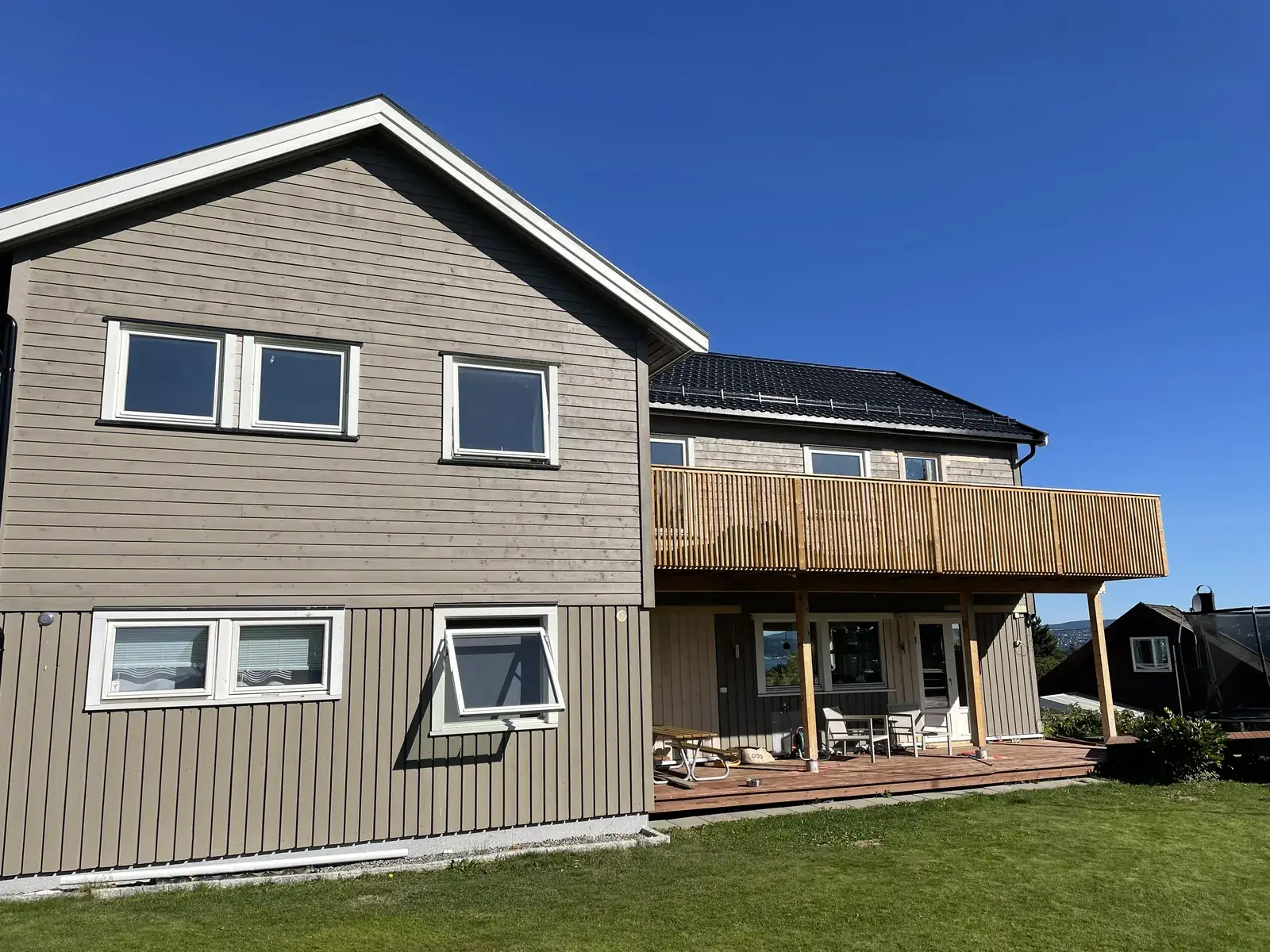 Ferdig påbygg på enebolig med ny trekledning, terrasse på bakkeplan og balkong med spilerekkverk