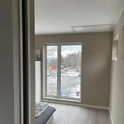 Ferdig oppusset rom med nytt gulv, malte vegger og stort vindu mot hagen